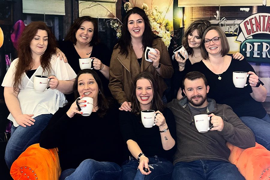 Team Members-Ellis-Insurance-Agency-Team-Members-Sitting-on-Couch-with-Branded-Coffee-Cups